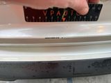 a person measuring the width of a car ' s bumper