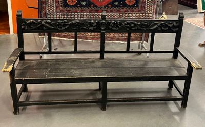 un banc qui se trouve dans une pièce où un tapis est accroché au mur