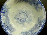 a blue and white plate sitting on a table next to a cup