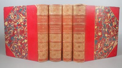 Quatre livres rouges sont alignés sur une table