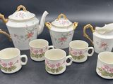 five cups and a teapot and a pitcher on the table