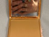 a gold compact case with a gold ring inside of it