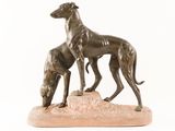 statue of two greyhounds standing on a rock on a white background