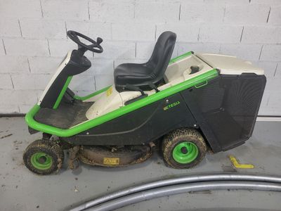 a green and black lawn mower sitting on top of a cement floor