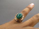une personne tenant une bague sertie d'une pierre verte
