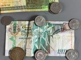 a pile of coins and a bank note on a table