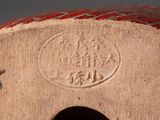 a close up of a red and white vase with a bird on it