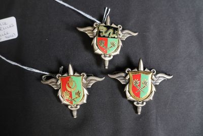 trois ornements en métal argenté et rouge sur un tissu noir
