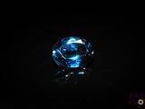 a close up of a blue diamond on a black surface