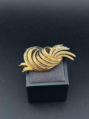 a close up of a gold brooch on a black box