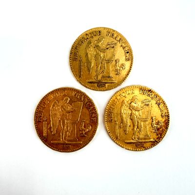 three gold coins sitting on top of each other on a white surface