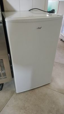 a small white refrigerator sitting in a kitchen next to a refrigerator freezer