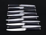several knives are lined up in a row on a black surface