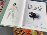 three books on a table with a drawing of a man and a bird