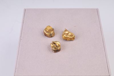 trois pépites d'or dans une boîte posée sur une surface blanche
