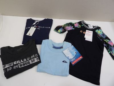 trois t-shirts et un t-shirt sont suspendus sur une étagère