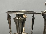 two silver vases sitting on top of a metal stand