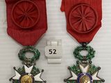 deux médailles sont exposées sur un fond blanc, ornées d'un ruban rouge
