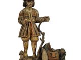 statue en bois représentant un homme avec un chien et des valises, sur fond blanc
