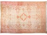 un tapis ancien orné d'un motif rose et beige sur fond blanc