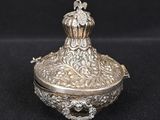 a silver plated box with a flower decoration on the lid