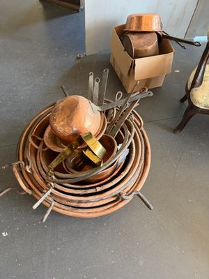 a pile of copper pots and pans sitting on the floor