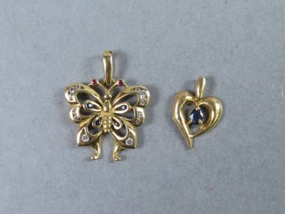 deux bijoux en or et diamants posés sur une surface grise