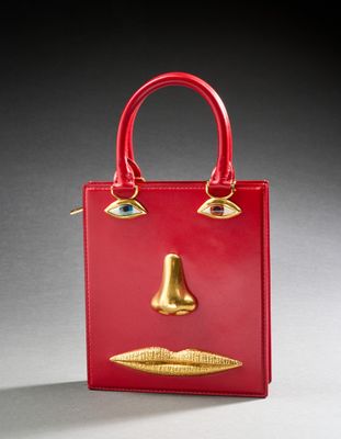 a close up of a red purse with a gold nose on it