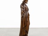a wooden statue of jesus holding a cross in his hands