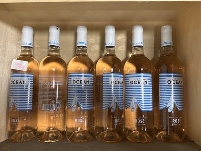 six bouteilles de vin rosé sont alignées dans une caisse en bois