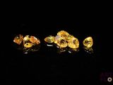 un gros plan sur un groupe de diamants jaunes posés sur une surface noire