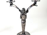a statue of a man holding two candelabs