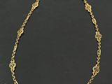 a gold plated necklace with a circular design on a black background