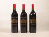 trois bouteilles de vin rouge posées l'une à côté de l'autre sur une surface blanche