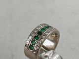 a close up of a ring with emerald stones on it