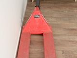 un chariot élévateur rouge posé dans un coin du salon