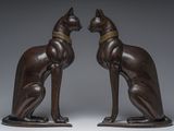 pair of bronze statues of a cat and a dog on a stand
