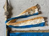 Gros plan sur un drapeau bleu et or orné d'une épée
