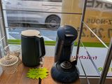 a coffee maker on a wooden table in front of a window