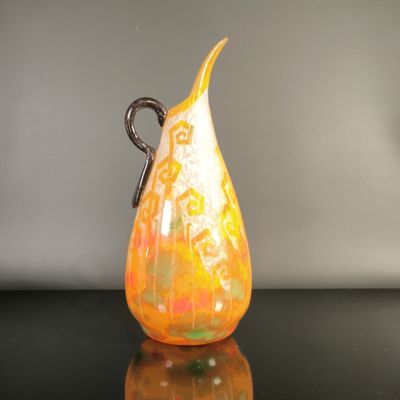 a yellow and orange vase sitting on a black table