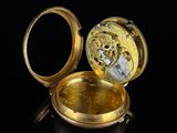 a gold pocket watch sitting on a black surface