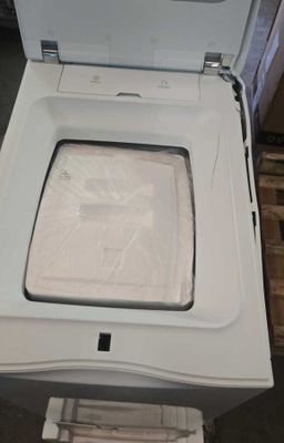une machine à laver blanche posée au sommet d'une pile de cartons