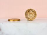 a gold coin sitting on top of a marble counter next to a pink wall