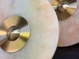 pair of white marble discs with gold metal discs on a black background