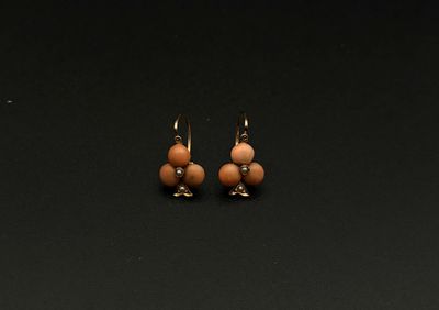 une paire de boucles d'oreilles ornées de perles, posée sur une surface noire