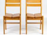 two wooden chairs sitting next to each other on a white surface
