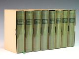 six livres verts sont alignés sur une surface blanche