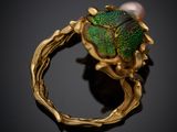 a close up of a gold ring with a green beetle on it