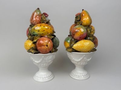 deux vases blancs contenant des fruits, posés sur une table