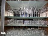many wine glasses on the glass shelves in the cabinet